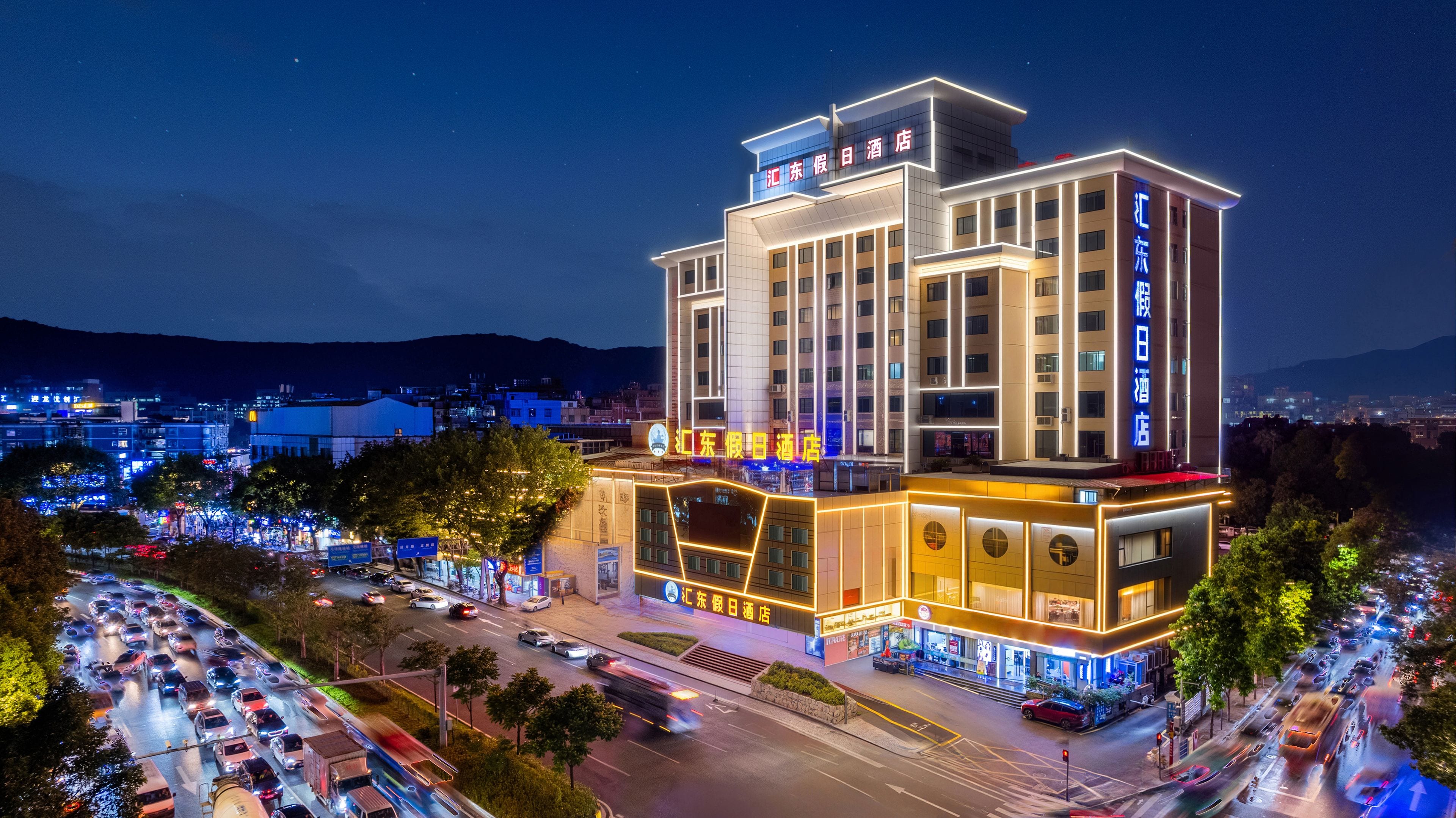 Ein mehrstöckiges Hotel mit auffälliger Beschilderung, umgeben von einer belebten Straße und weiteren Gebäuden.