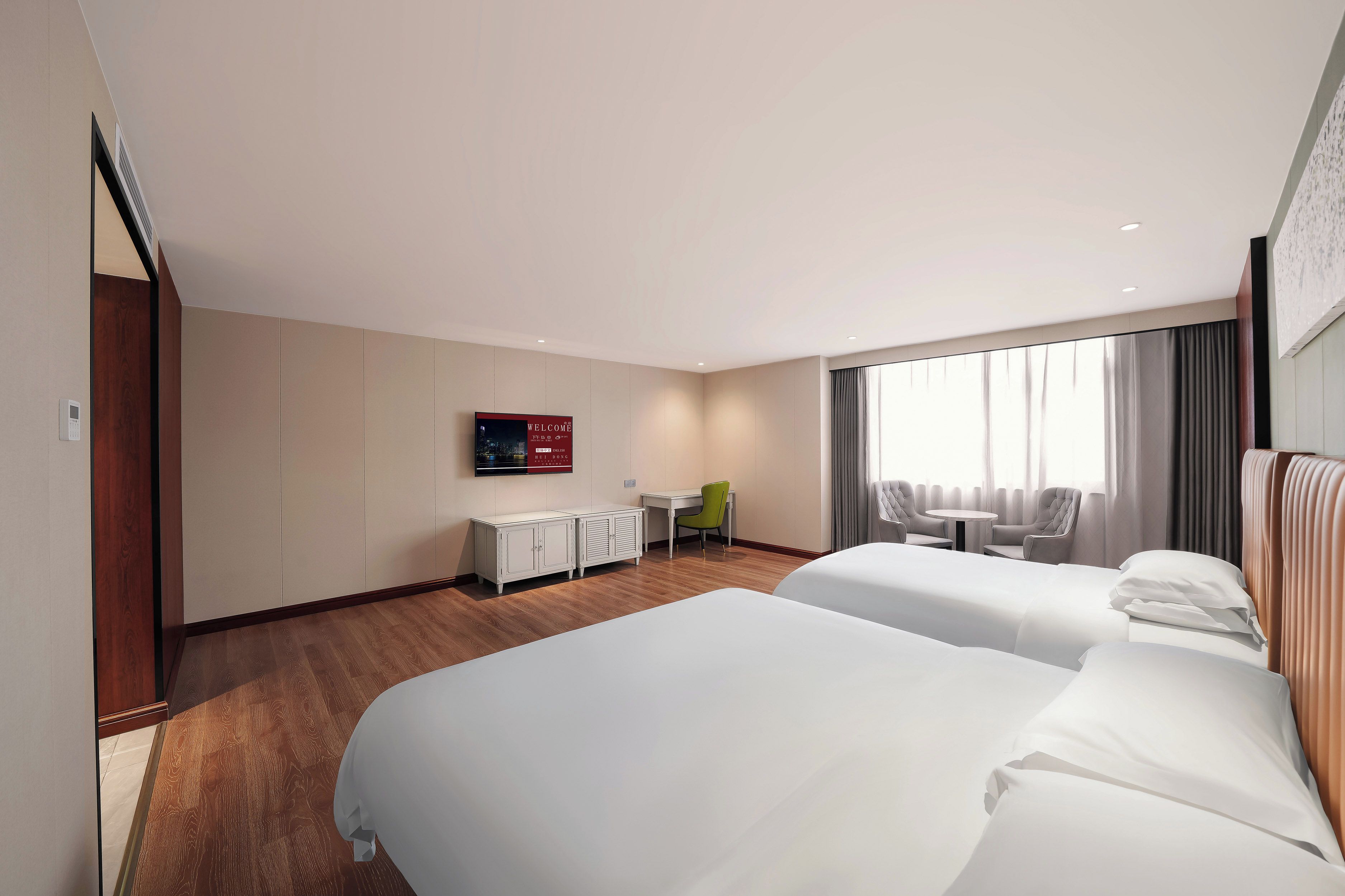 Habitación de hotel con dos camas, un escritorio, una silla y un televisor en la pared.