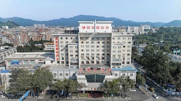 A multi-story hotel with a modern facade, located in an urban area with a view of distant mountains.