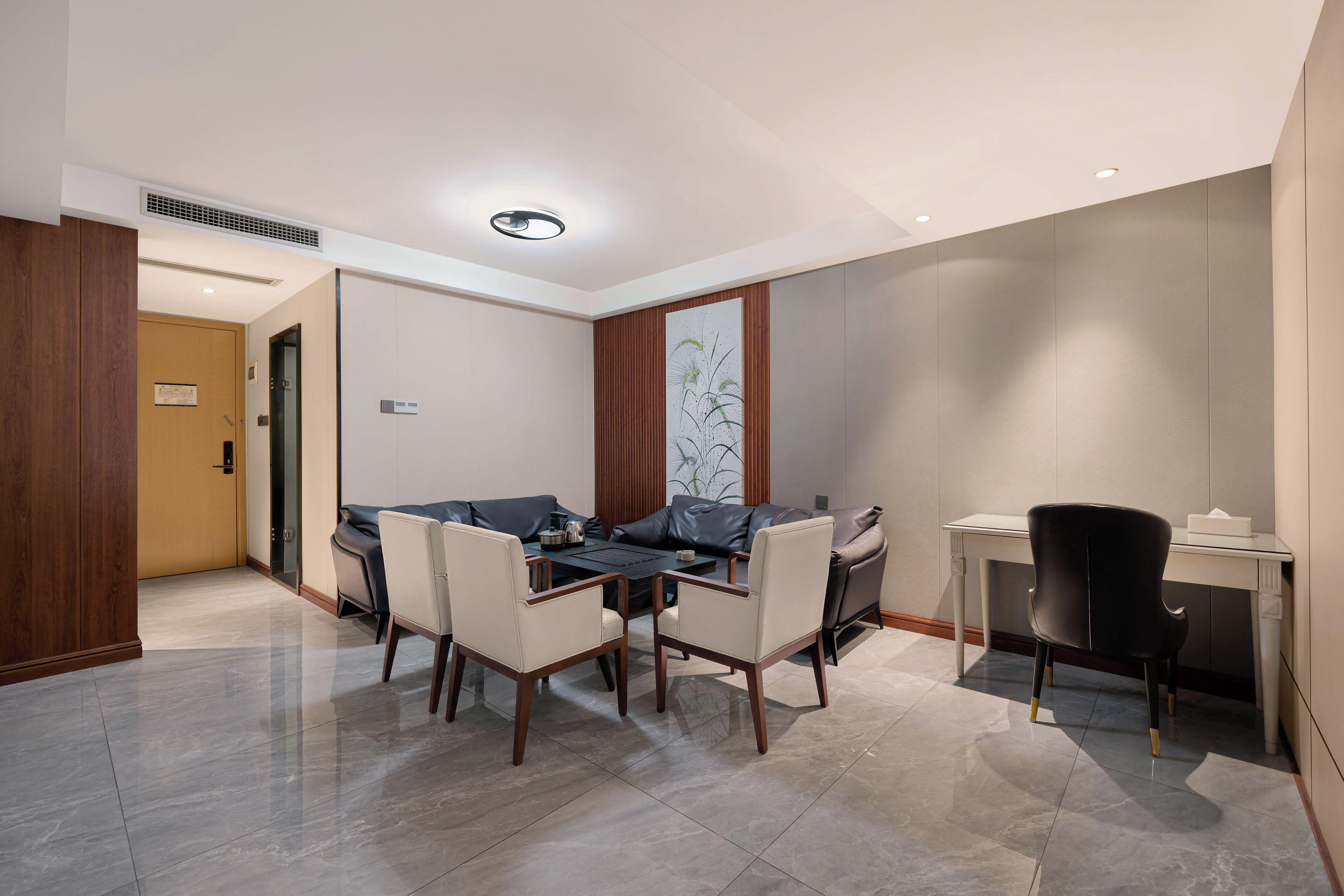 A modern hotel room with a dining area, a sofa, a desk, and a chair.