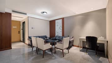 A modern hotel room with a dining area, a sofa, a desk, and a chair.