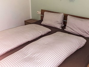 A single bed with a checkered bedspread and two pillows.