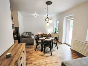 A modern living space with a wooden dining table, black chairs, and a sofa. - Cosy apartment for 4 guests with WIFI, TV, balcony and pets allowed (Dvůr Králové Nad Labem)