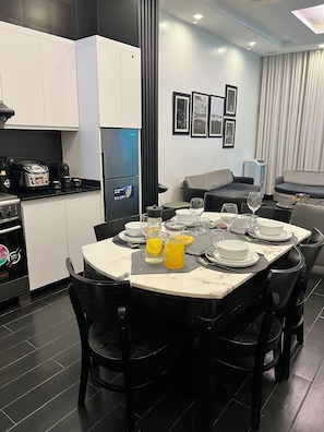 Cozinha moderna com área de jantar, destacando uma bancada de mármore, cadeiras pretas e uma mesa posta para refeição.
