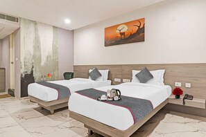 Habitación de hotel con dos camas, un cuadro, un jarrón con flores y un teléfono en la mesita de noche.