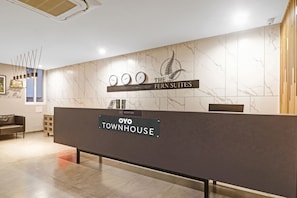 Eine Rezeption mit einem Schild für das Hotel 'The Fern Suites' und 'Oyo Townhouse'.