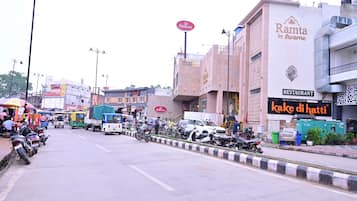 A street with parked motorcycles and vehicles, a restaurant named 'Rama by Avansha' with a signboard, and a building with a sign for 'Haldiram's'.