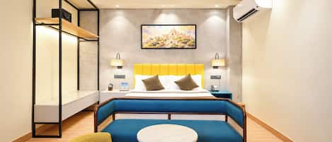 Une chambre d’hôtel comprenant un lit, un canapé, une petite table, une chaise, un ventilateur de plafond et un appareil de climatisation.