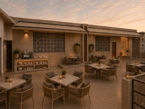 An outdoor patio with multiple tables and chairs, a coffee station, and decorative wall panels. - Hotel Ramta by Avarna (Ayodhya)