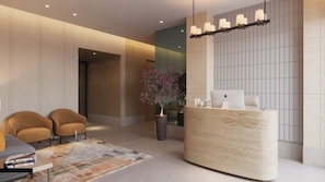 Un área de recepción moderna con un mostrador curvo, dos sillones, una planta en maceta y un ordenador portátil Apple sobre el mostrador.