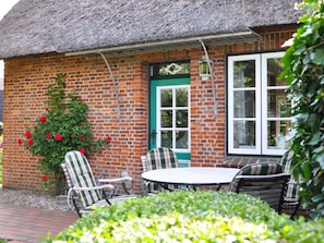 A brick building with a thatched roof, a green door, and a window with white frames. - Karoline House Apartment Jule (Utersum)