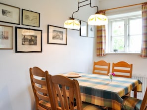 A dining area with a table set for two, wooden chairs, and a window with curtains. - Karoline House Apartment Jule (Utersum)
