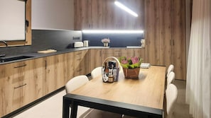 A modern kitchen with wooden cabinets, a black countertop, and a dining table with chairs. - Designed pyrenean farmhouse at 1,100 m altitude (Ribera d’Urgellet)
