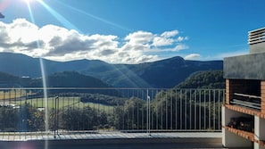A balcony with a view of a mountainous landscape, a clear sky, and a modern building structure. - Designed pyrenean farmhouse at 1,100 m altitude (Ribera d’Urgellet)