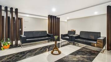Uma área de espera moderna com dois sofás, uma mesinha e um vaso de planta.