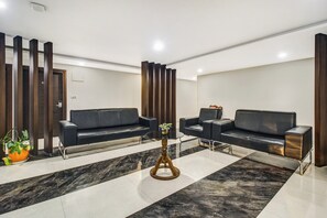 Uma área de espera moderna com dois sofás, uma mesinha e um vaso de planta.