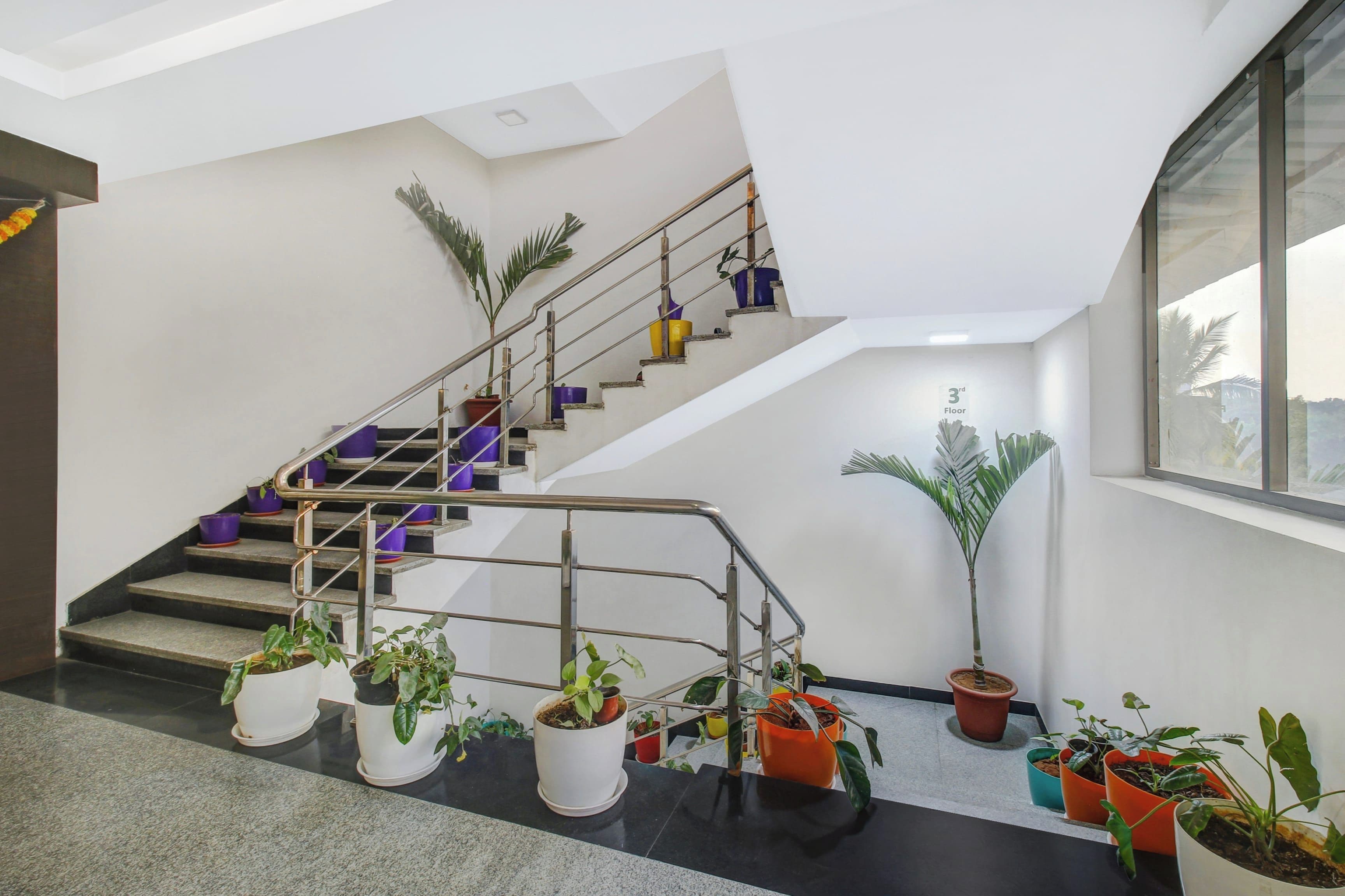 Una escalera con barandillas de metal, plantas en macetas y un letrero que indica '3rd Floor'.