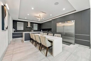 A modern kitchen with a central island, stainless steel appliances, and a dining area with chairs. - Walk to Raymond James Stadium - Modern Tampa Home with 2 King Beds, Balcony & Outdoor Dining (Tampa)