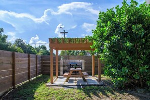A wooden pergola with a grill and seating area in a backyard. - Walk to Raymond James Stadium - Modern Tampa Home with 2 King Beds, Balcony & Outdoor Dining (Tampa)
