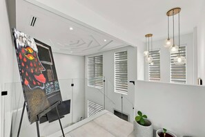 Ein modernes Interieur mit Treppe, einem Gemälde an der Wand und Pendelleuchten.