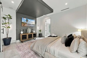 Ein modernes Schlafzimmer mit Bett, Fernseher, Schrank und einer Topfpflanze.