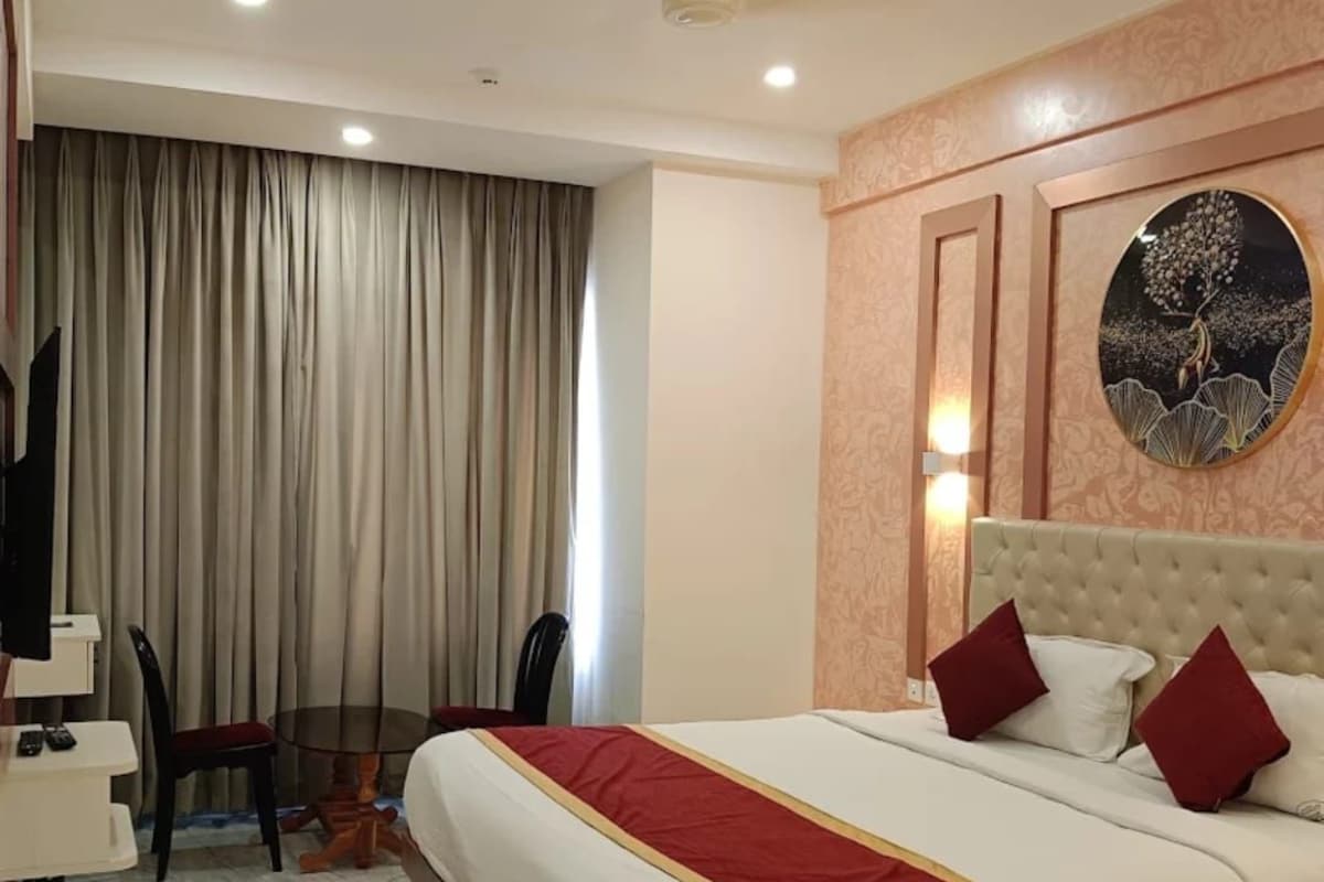 Una camera d'albergo con un letto, una scrivania, una sedia e un'ampia finestra con tende.