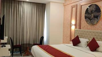 Una camera d'albergo con un letto, una scrivania, una sedia e un'ampia finestra con tende.