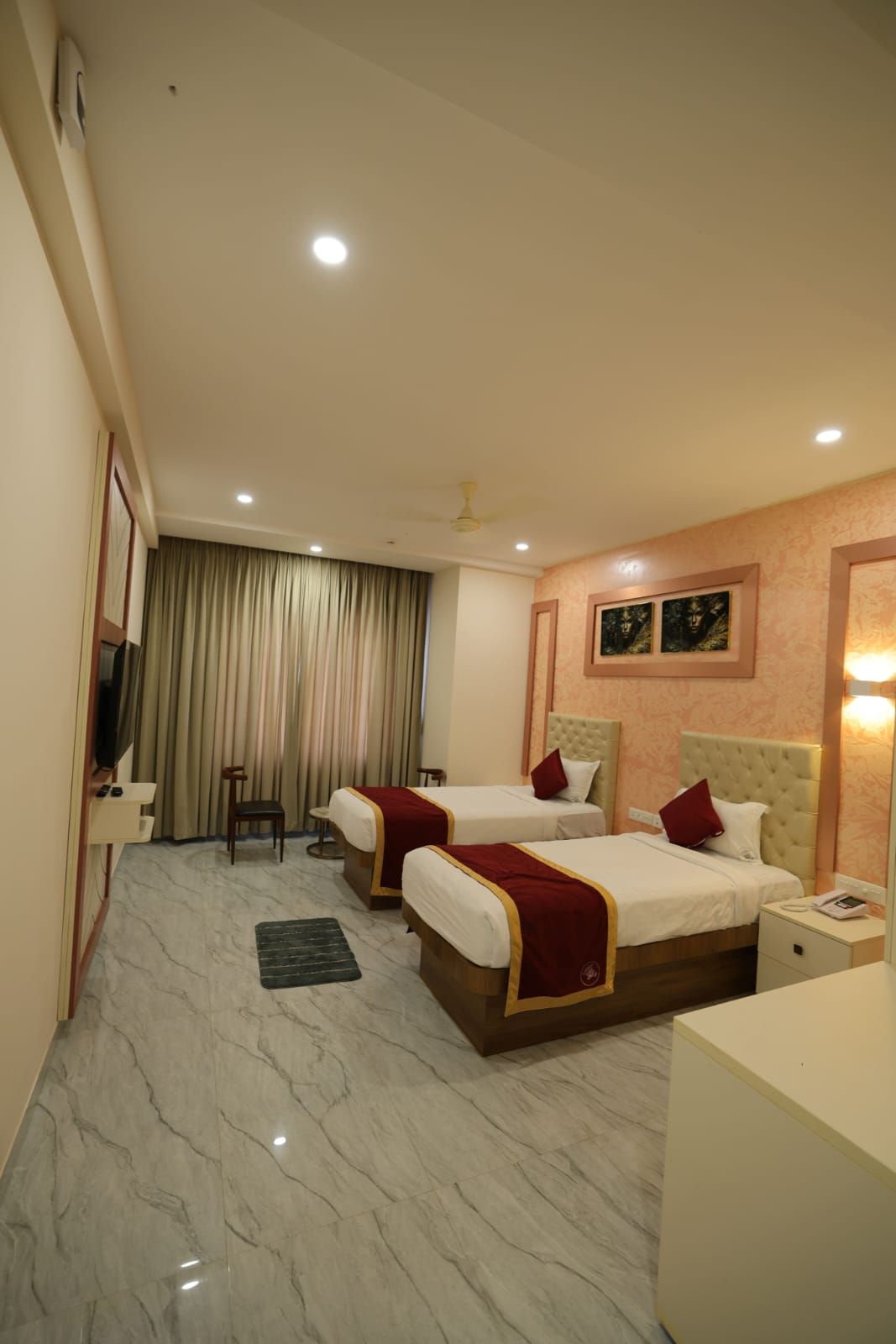 A hotel room with two beds, a TV, a desk, and a chair.