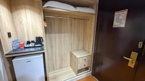A compact room with a kitchenette area, a small wooden cabinet, and a door with a sign. - Al Massa Al Ayam Hotel (Makkah)