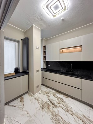 A modern kitchen with marble flooring, built-in cabinets, and a window with curtains. - Cerano8 Design Apartment - Fashion District (Milano)
