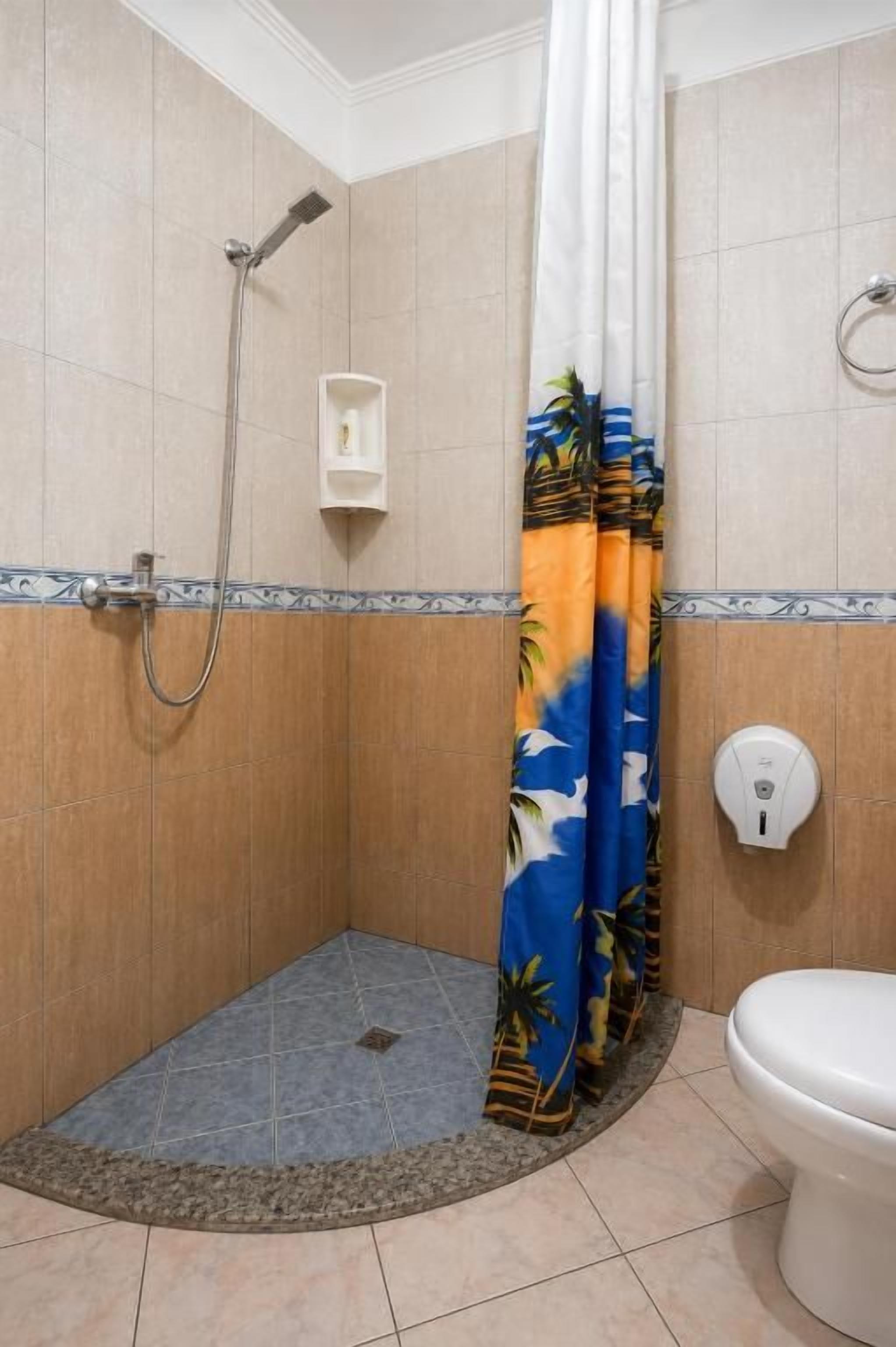 Een badkamer met een douche, toilet en een handdoekhouder.