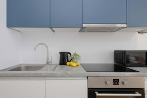 A modern kitchen with a sink, stove, and microwave. - Warsaw | Krochmalna 61 | Modern Studio | Air Conditioning (Warszawa)