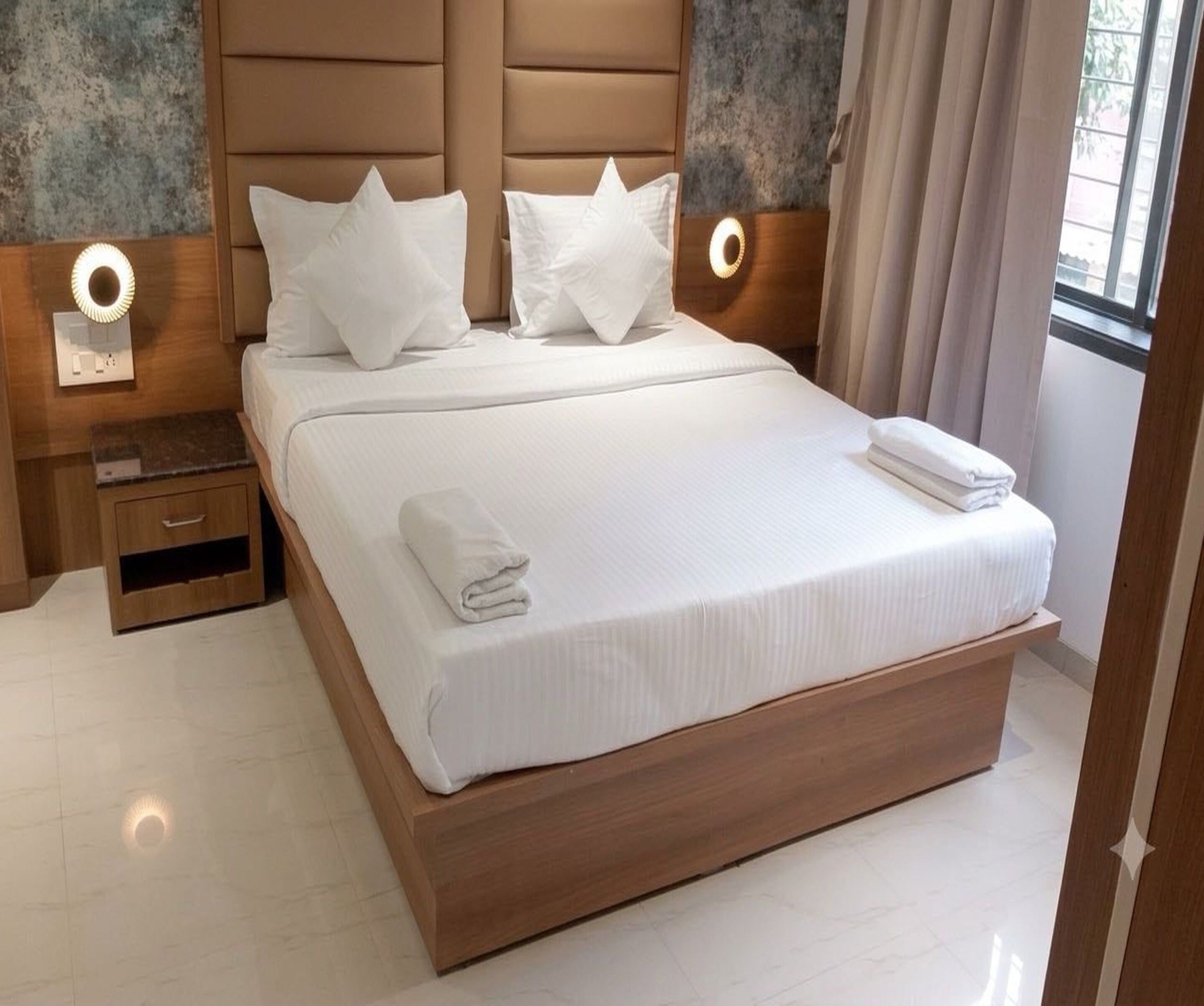 A large bed with a wooden headboard, white bedding, and two bedside tables with lamps.