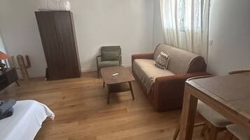 A living room with a sofa, a small table, a wooden cabinet, and a hanging light fixture.