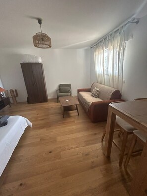 Una sala de estar con un sofá, una mesita, un aparador de madera y una lámpara colgante.