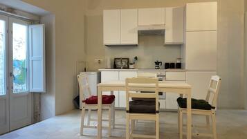 A compact kitchen with a dining table and chairs, a built-in oven, and a window with a view.