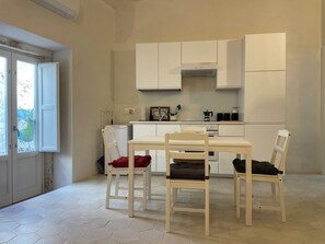Eine kompakte Küche mit Esstisch und Stühlen, inklusive Backofen und einem Fenster mit Aussicht.