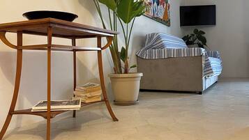 Un salon avec une table en bois, une plante en pot, un canapé et un tapis rouge.