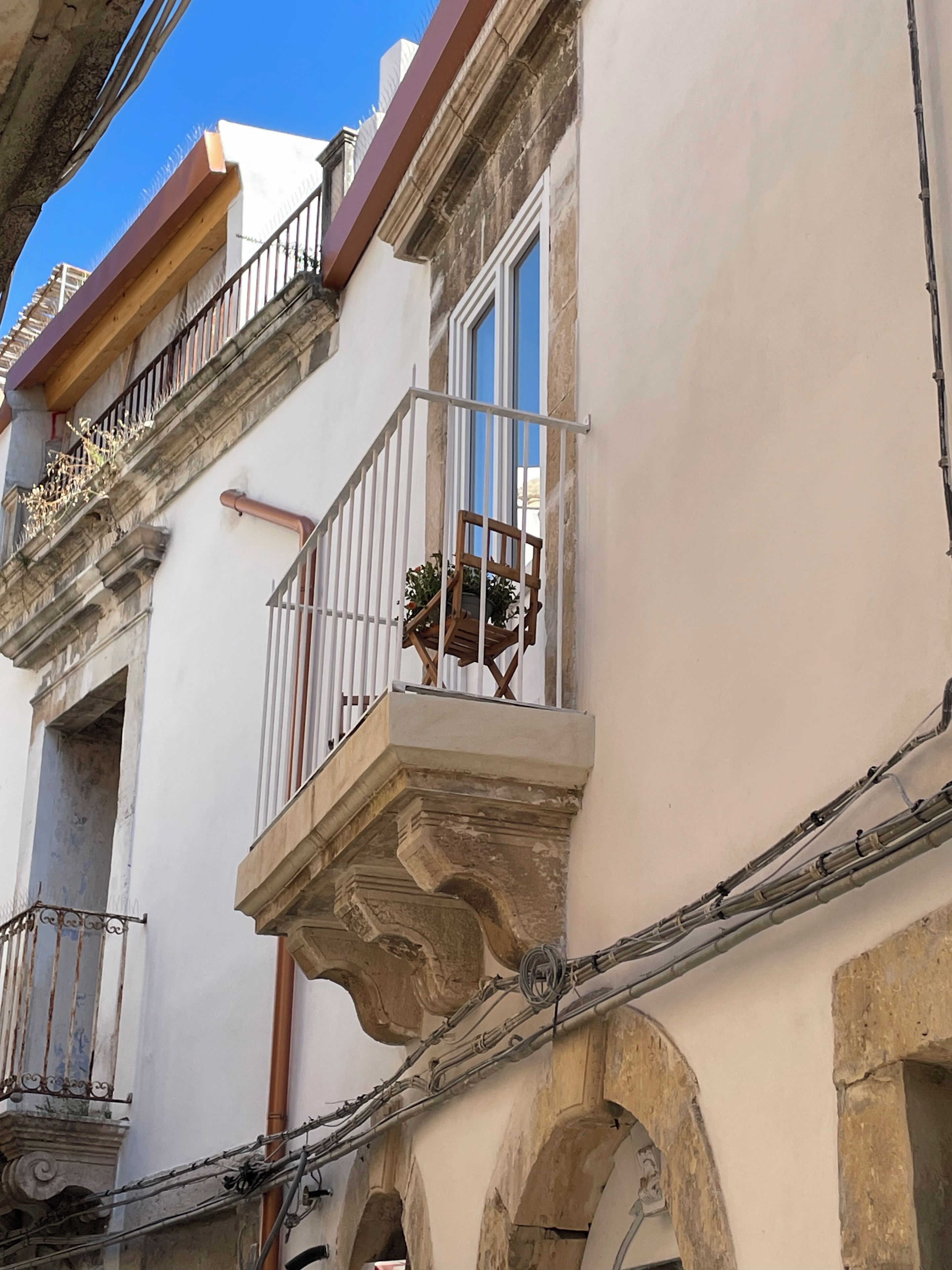 Un bâtiment doté d’un balcon, d’une fenêtre et de détails architecturaux apparents, tels que des arches et une balustrade.