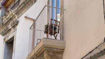 Un bâtiment doté d’un balcon, d’une fenêtre et de détails architecturaux apparents, tels que des arches et une balustrade.