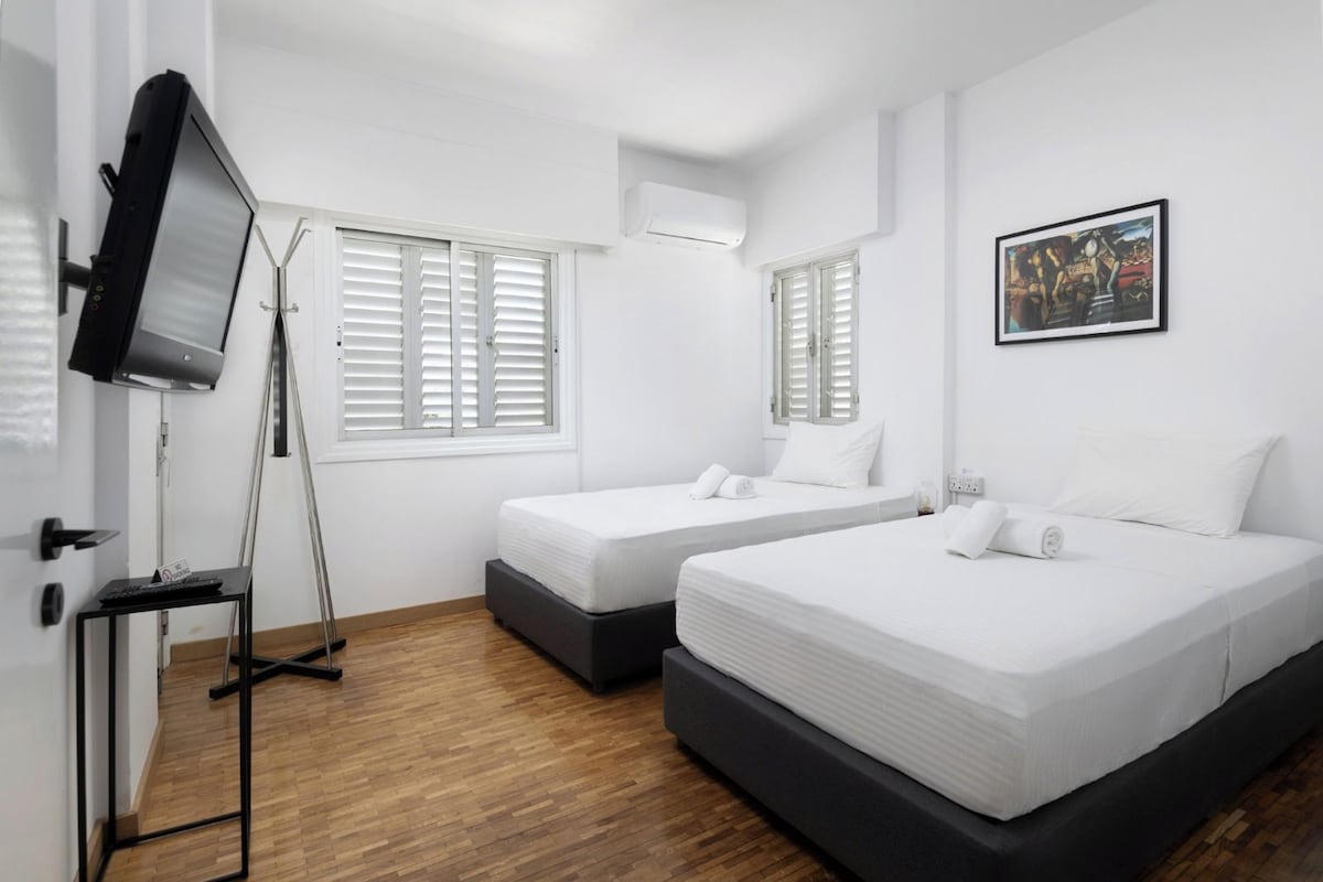 Habitación de hotel con dos camas, un televisor y un cuadro en la pared.