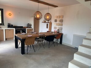Una cocina moderna con una mesa de madera dispuesta para comer, una cafetera y un horno empotrado.