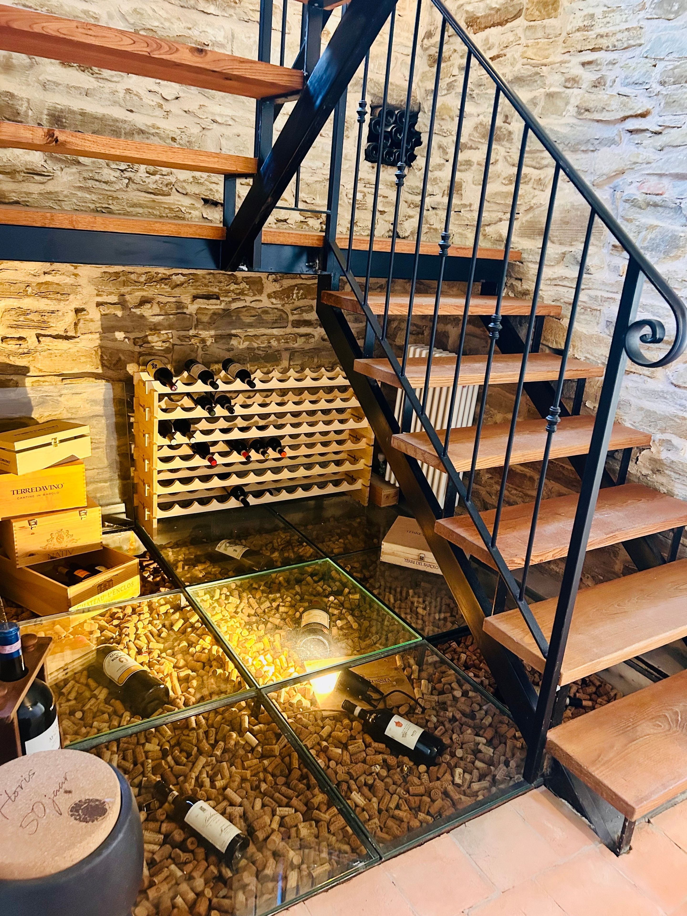 A staircase with a stone wall background, wooden steps, and metal railings.