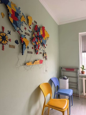 Ein Zimmer mit einer Wandkarte, zwei Stühlen, einem Heizkörper und einem Fenster.