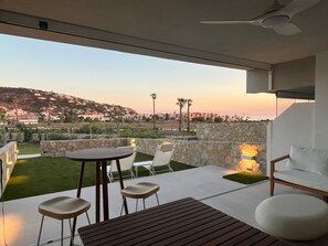 Una moderna terrazza esterna con tavolo e sedie, pareti in pietra e vista su una cittadina collinare.