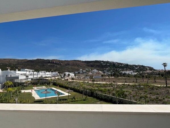 Quartiere residenziale con edifici bianchi, una piscina e un paesaggio collinare sullo sfondo.