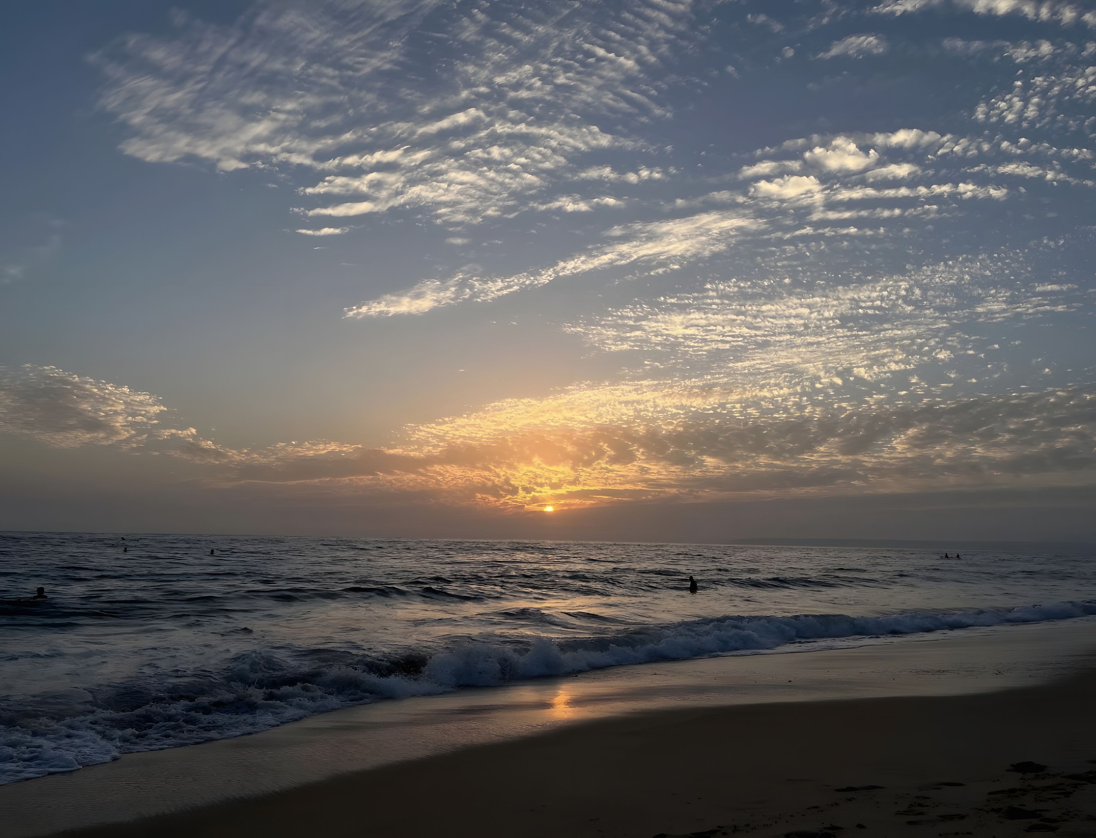 A beach with waves and a sunset.