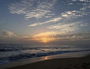 A beach with waves and a sunset.