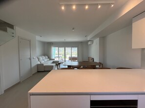 Una sala de estar moderna con un sofá, una mesa de comedor y un ventanal grande.