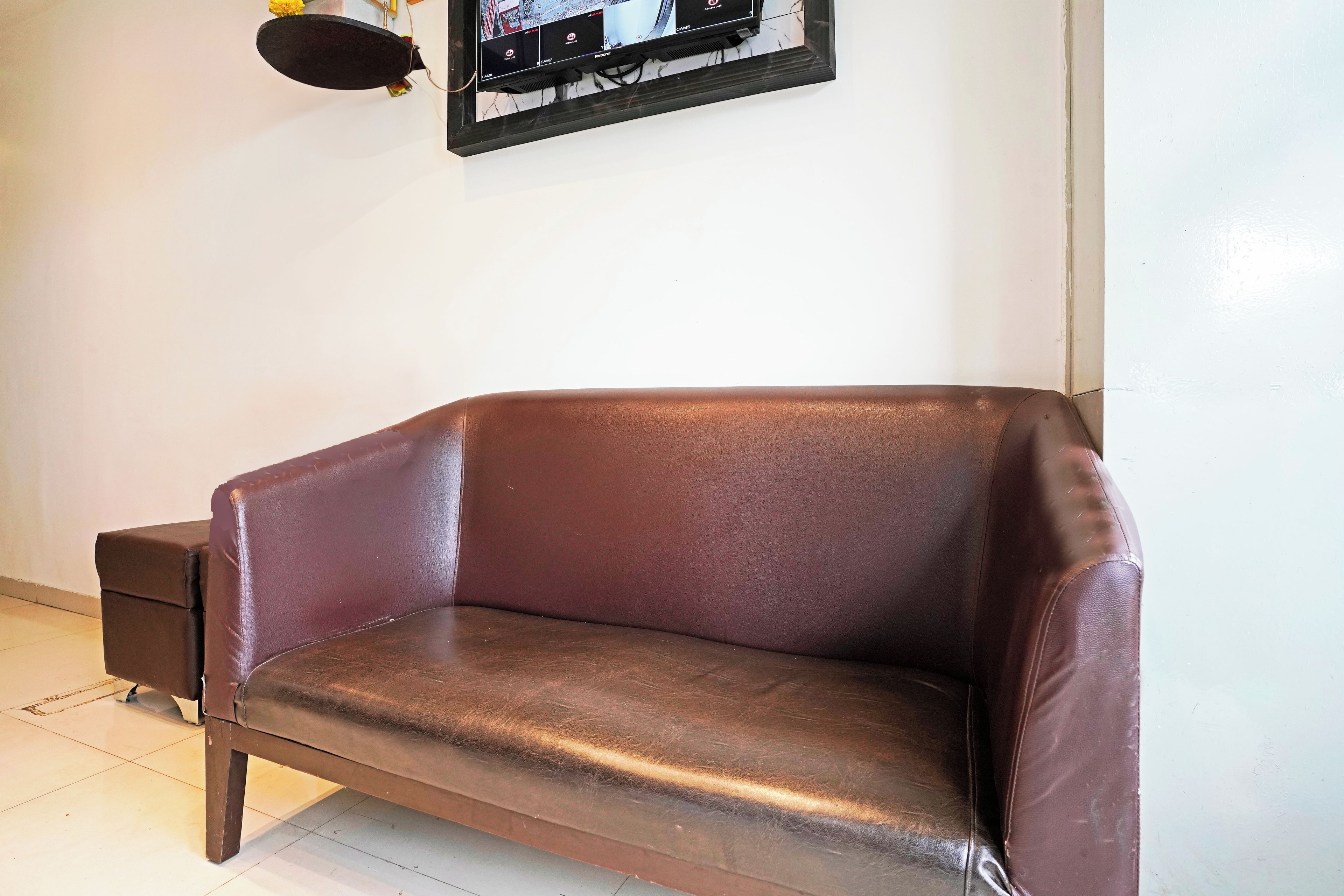 A brown leather sofa with a wooden frame against a white wall.